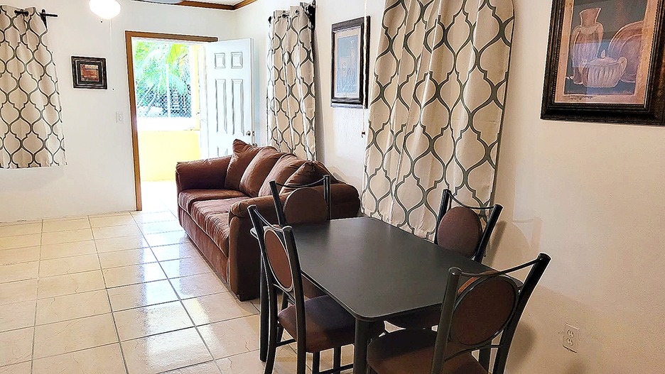 Living room with dining table and sofa, featuring patterned curtains and framed wall art