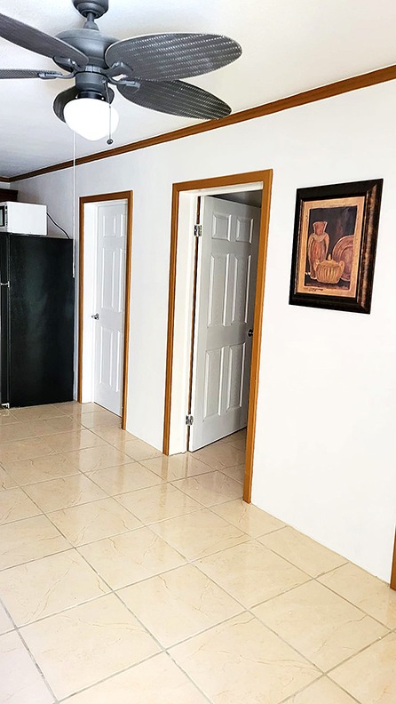 Interior hallway with two white doors, a black fridge, and a ceiling fan with a light