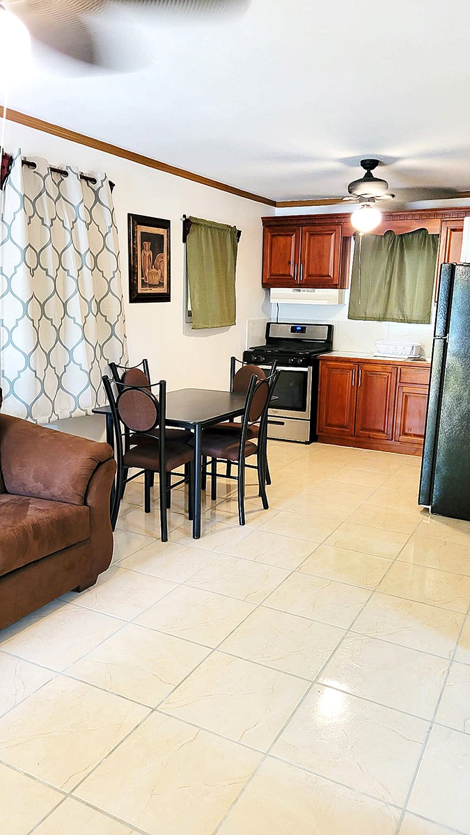 Indoor kitchen and dining area with a table, chairs, a stove, cabinets, and a ceiling fan
