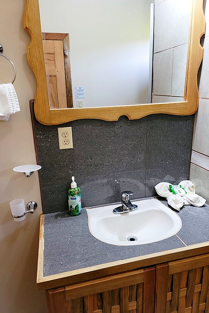 Bathroom vanity with a wooden mirror, a stone countertop, and a small hand towel decoration
